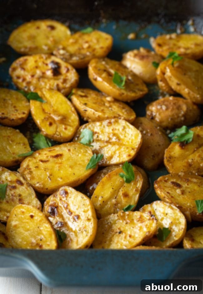 Roasted lemon garlic potatoes, golden and crispy, in a blue baking dish.