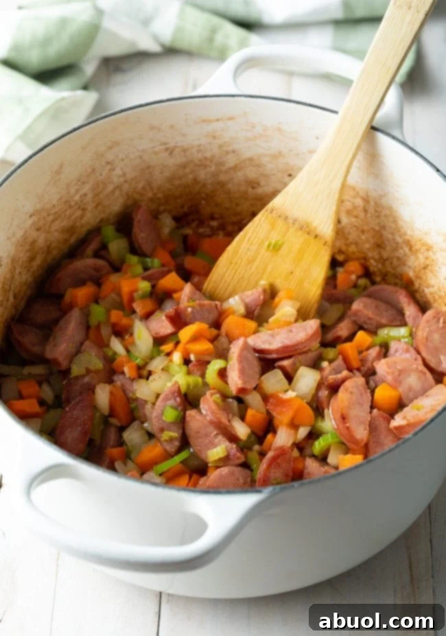 Southern Comfort Chicken Bog 6 Aromatic blend of sautéed vegetables (onion, carrots, celery, garlic) and smoky sausage browning together in a large pot.