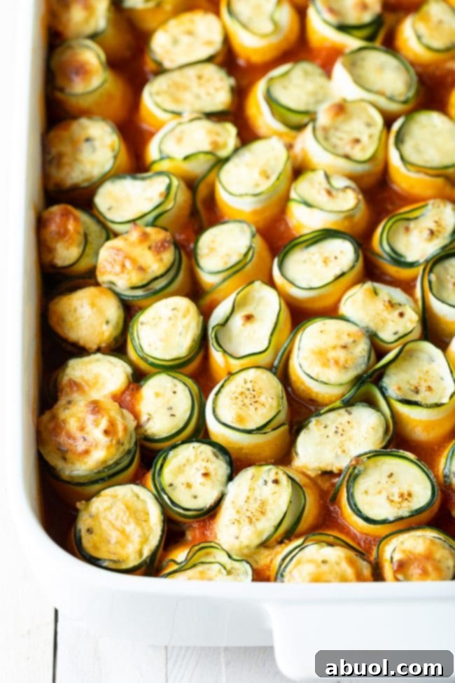 low carb keto zucchini roll ups in a white baking dish.