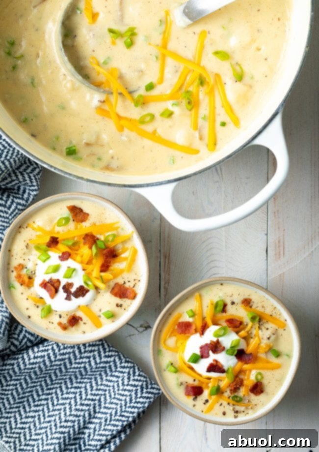 Cozy Stovetop Potato Soup 4 An overhead shot showcasing two inviting bowls of loaded potato soup, with a large Dutch oven filled with more soup nearby, ready to serve.