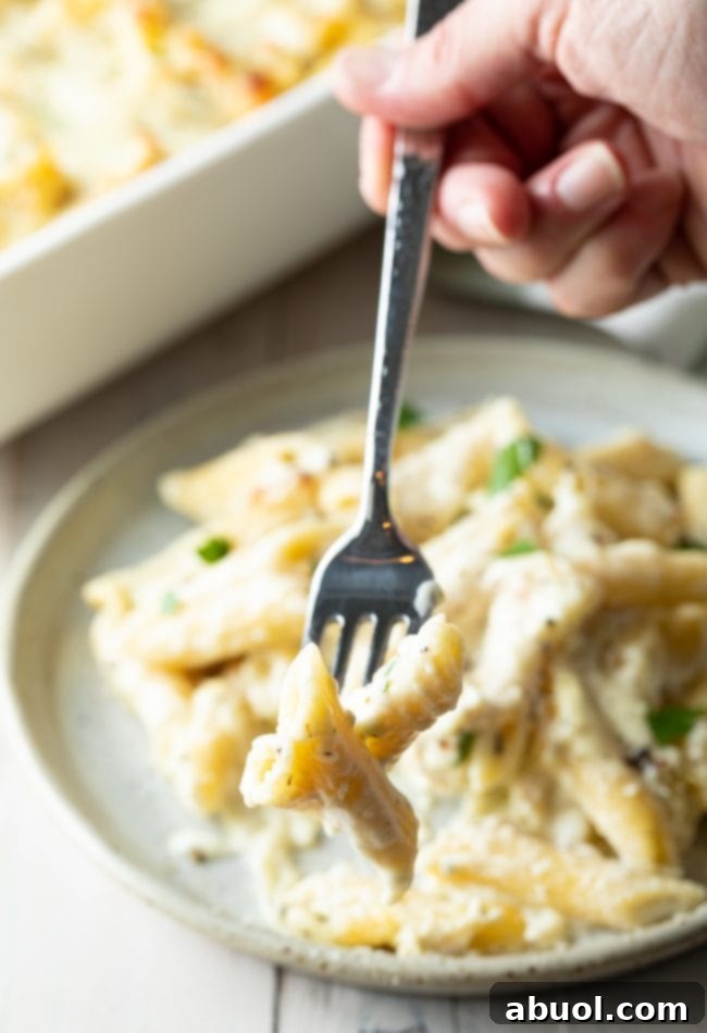Close-up of a fork lifting a bite of cheesy pasta, showing the melted cheese and creamy texture.