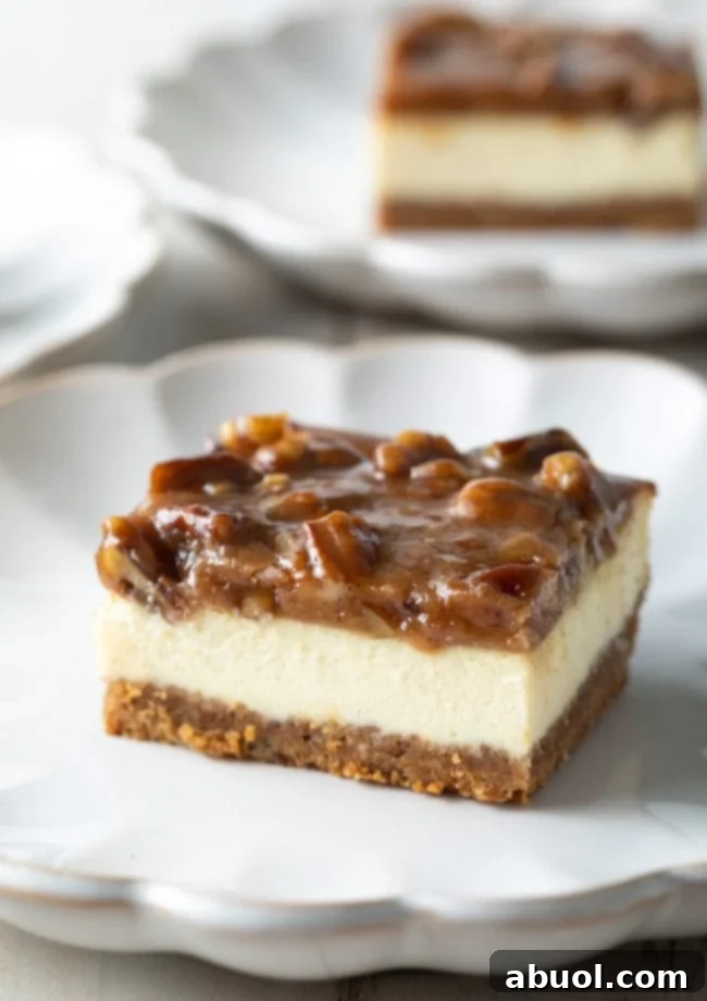 A perfectly portioned pecan pie cheesecake bar resting on a white plate, showcasing its distinct layers and tempting pecan topping. 