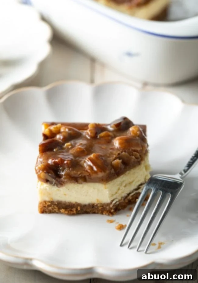 A beautiful piece of pecan pie cheesecake with a rich caramel pecan topping, served on a plate with a fork, a bite already taken.
