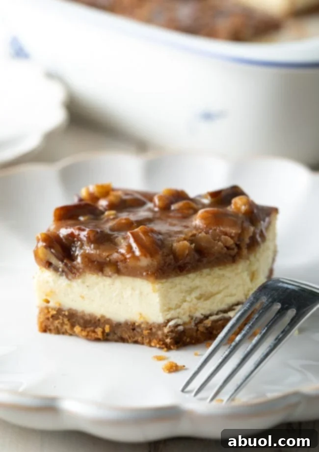 A close-up of a single pecan pie cheesecake bar on a plate, with a bite taken out, revealing the creamy cheesecake layer beneath the pecan topping.
