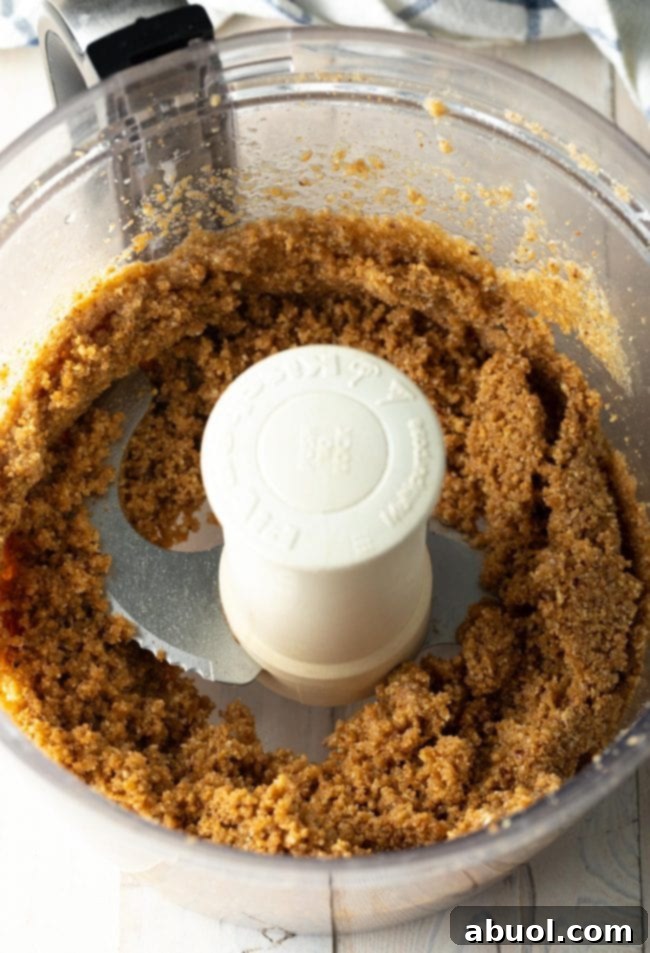 The graham cracker crust mixture being combined in the food processor, showing the texture before pressing into the pan.