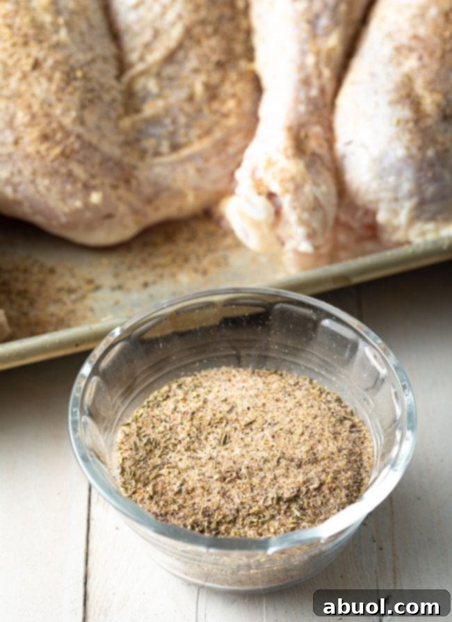 A bowl filled with homemade spatchcock turkey spice rub, featuring a blend of salt, pepper, garlic powder, onion powder, and aromatic herbs.