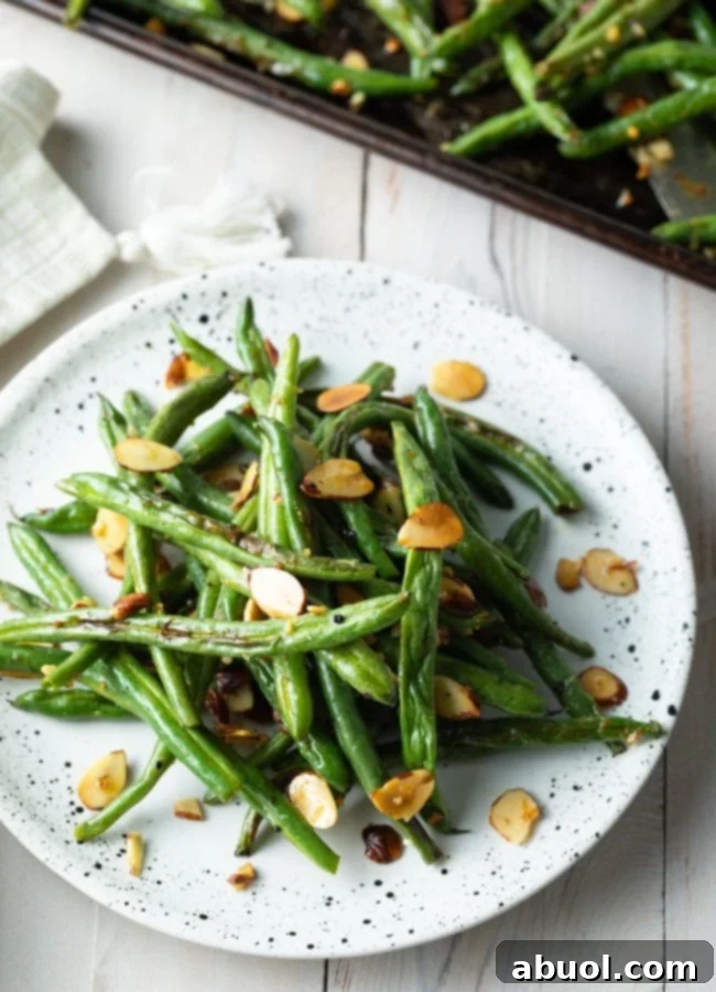 Roasted green bean almondine piles on a plate, ready to serve
