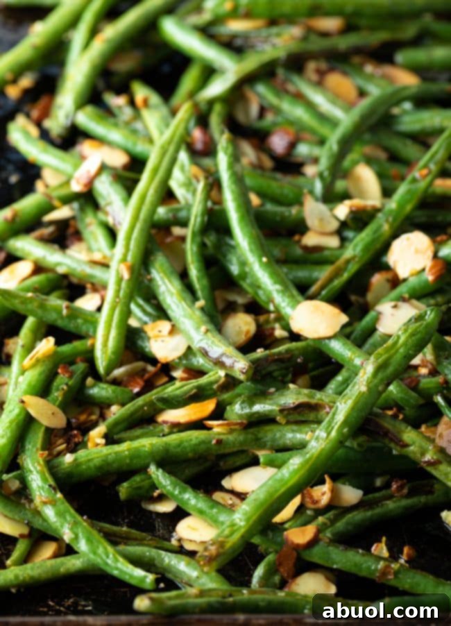 Baked green bean almondine recipe in the oven on a sheet pan, showcasing ease of preparation