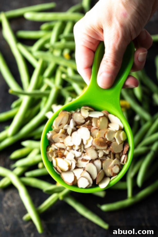 Adding sliced almonds to green beans on a baking pan before roasting