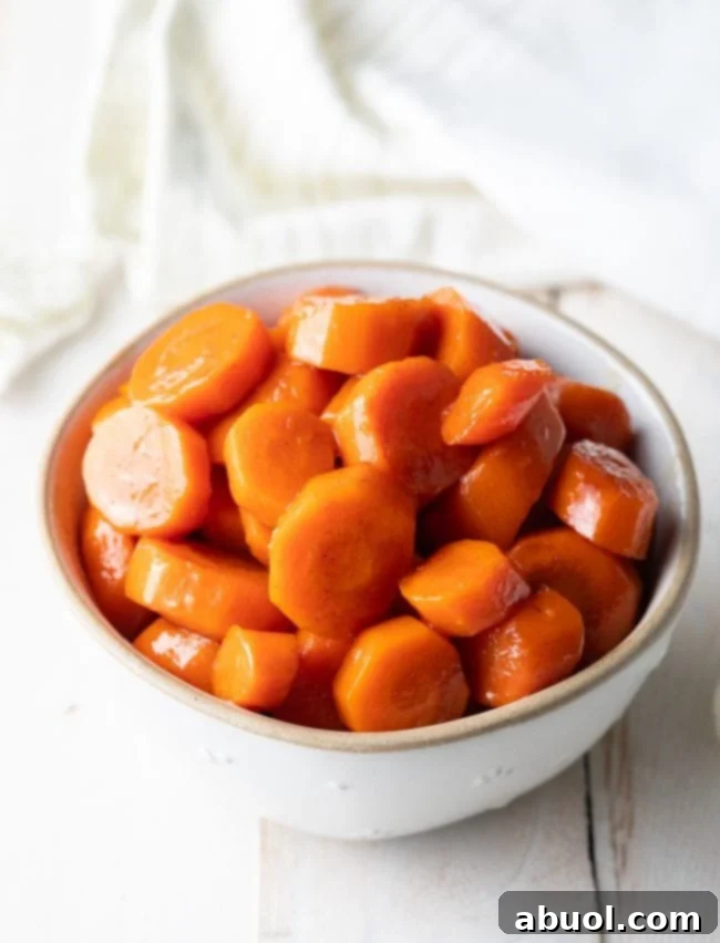 A bowl of glossy, vibrant Maple Glazed Carrots with Cinnamon, ready to serve as a perfect fall side dish.