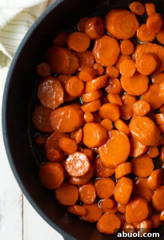 Maple Glazed Carrots with Cinnamon cooking in a saute pan, showcasing the glazing process.