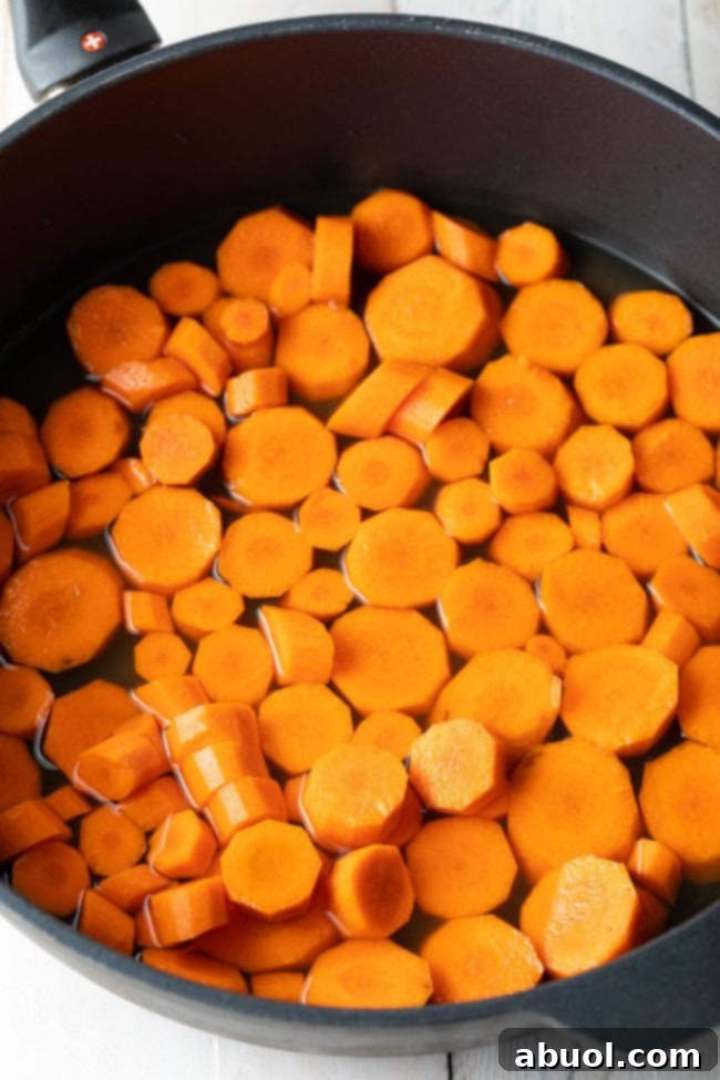 Carrots steaming in a skillet, softening before the glaze is added.