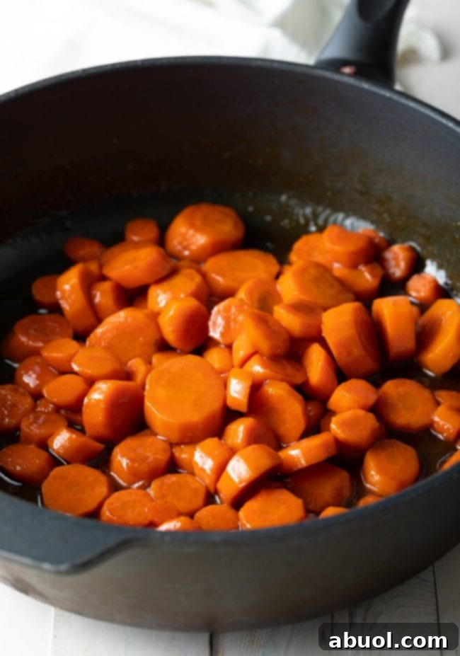 Candied Carrots with Maple Syrup Recipe with glaze shown in a skillet before serving.