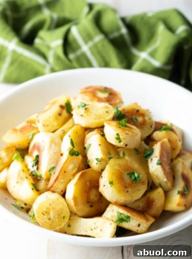Savory Garlic Butter Parsnips 2 A bowl filled with golden-brown garlic butter roasted parsnips, garnished with fresh parsley.