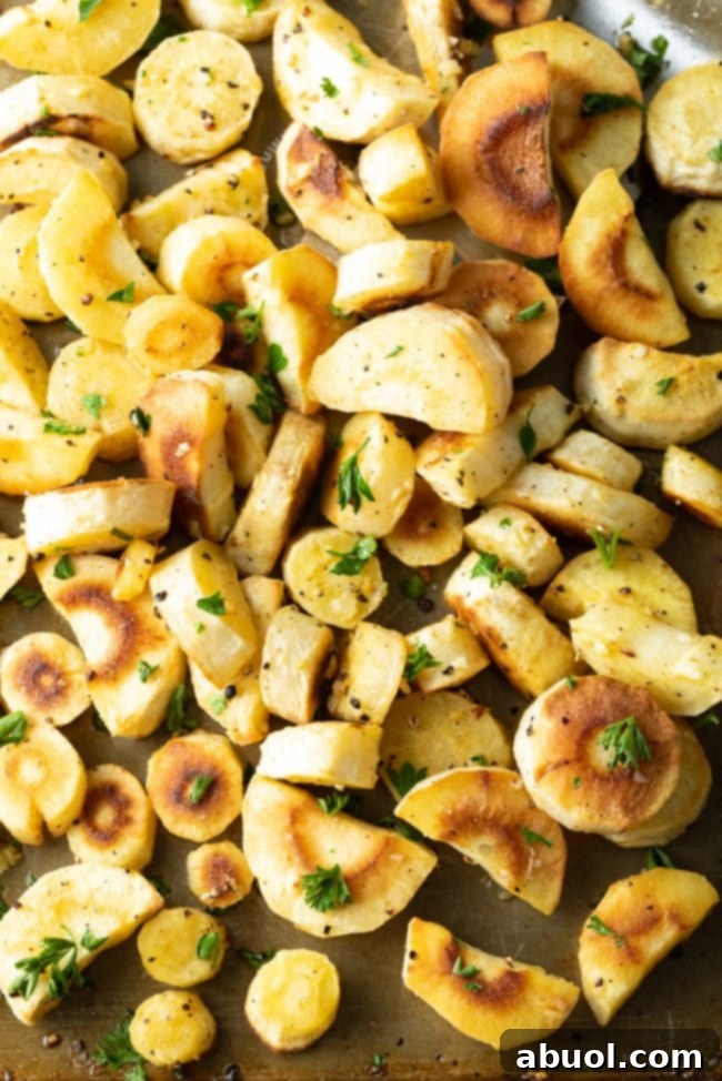 Savory Garlic Butter Parsnips 8 A large serving bowl filled with oven roasted parsnips coated in garlic butter, garnished with fresh herbs.