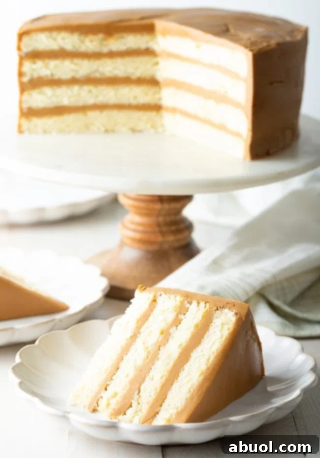 southern caramel cake with salted caramel frosting on a cake stand with a piece of cake on a plate