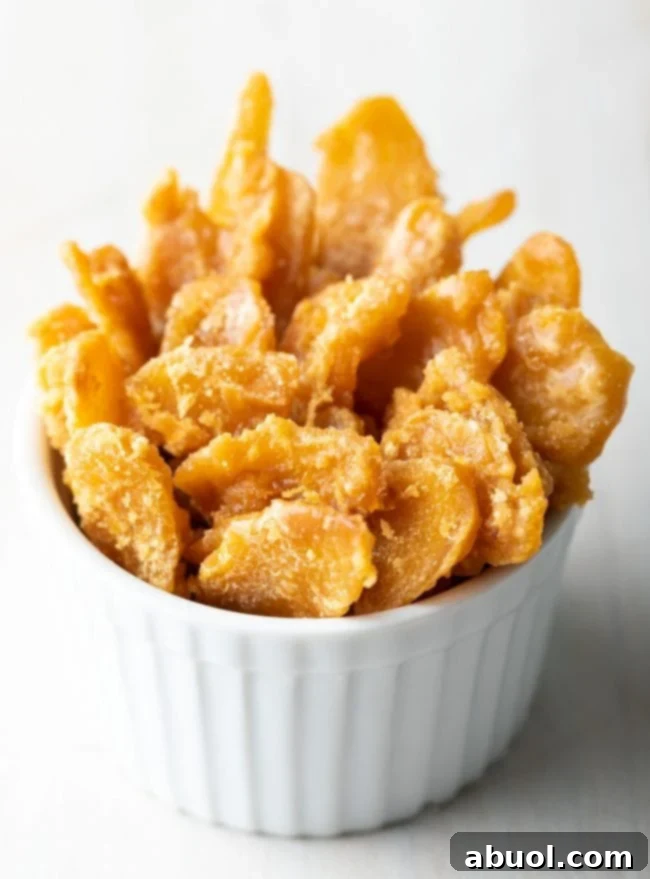 A small, elegant ramekin bowl brimming with perfectly candied ginger, showcasing its golden hue and inviting texture, ready for enjoyment.