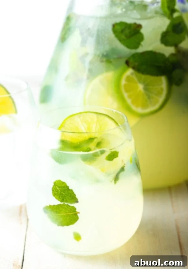 Perfect mojitos poured into glasses, garnished with mint and lime.