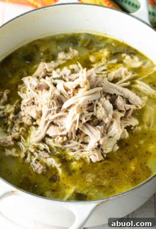 Shredded chicken being added back into the Pozole Verde pot. 