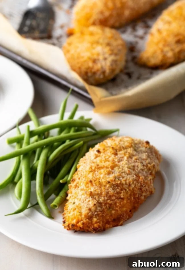 Crispy baked buffalo chicken breast recipe on plate with vibrant green beans, showcasing a healthy and delicious meal.