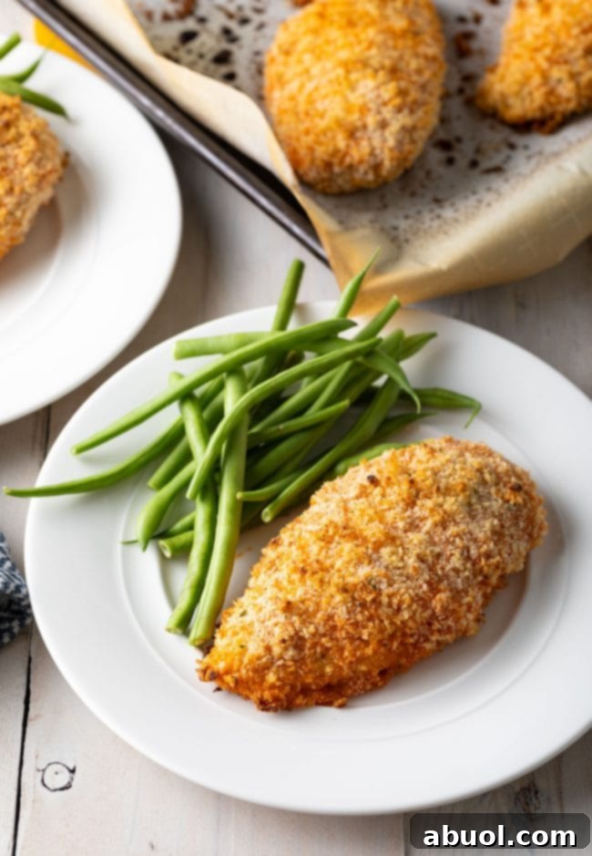 Oven-baked buffalo chicken breast plated, with a baking sheet visible in the background, highlighting the ease of preparation.