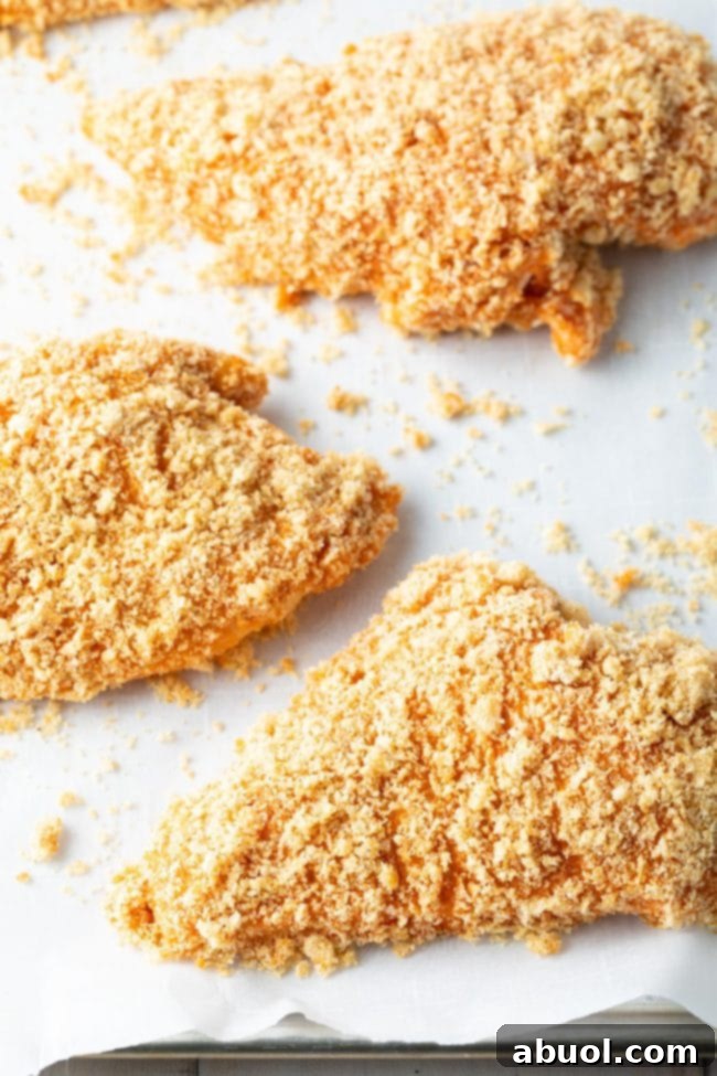 Chicken breasts on a baking sheet with a buffalo Panko crust, perfectly ready for the oven.
