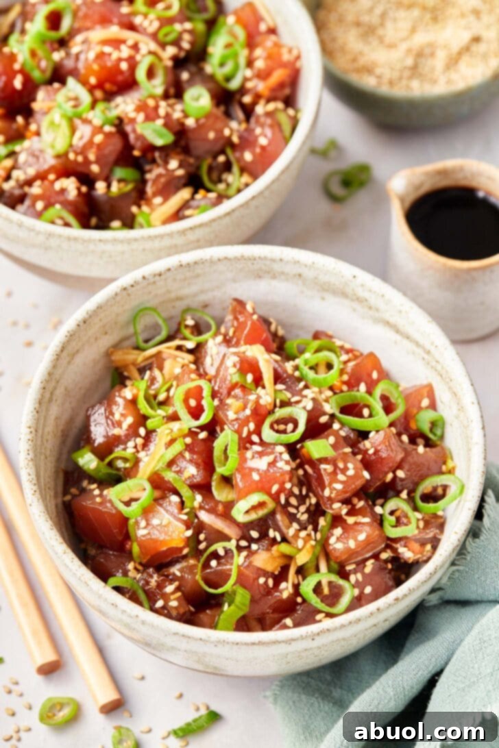 Two bowls of freshly prepared Hawaiian Ahi Poke, garnished and ready to serve, with a small dish of soy sauce on the side.