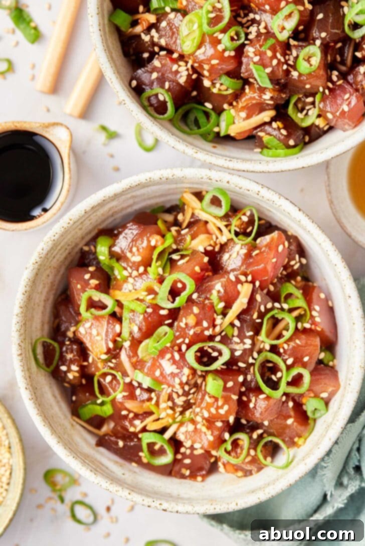 A beautifully plated bowl of tuna poke, garnished with freshly chopped scallions and a generous sprinkle of sesame seeds, showcasing its vibrant colors and inviting texture.