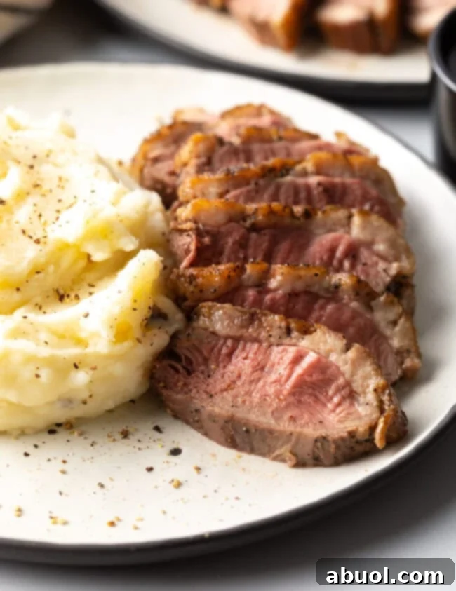 Sliced duck breast recipe served with creamy mashed potatoes and pan sauce