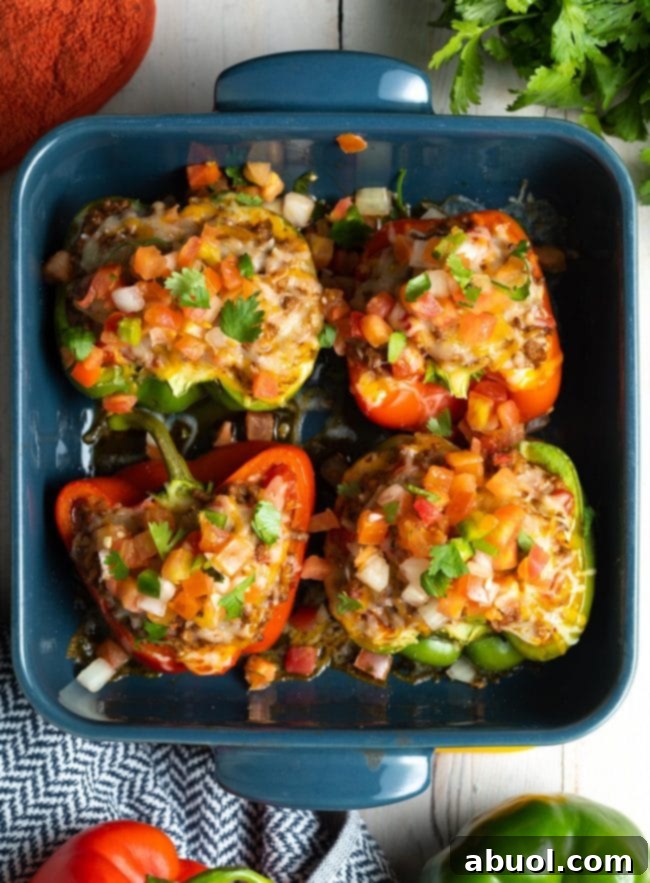 Hearty Keto Stuffed Peppers 3 Overhead view of several low carb stuffed peppers recipe in a ceramic baking dish, ready to be served.