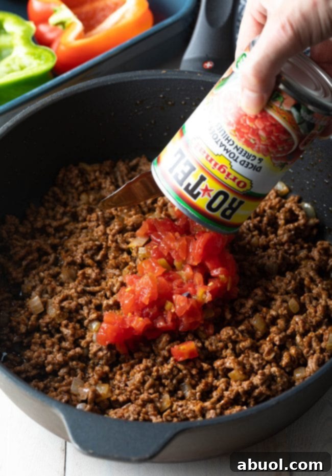 Hearty Keto Stuffed Peppers 5 Ground beef, Rotel diced tomatoes, and green chilies simmering in a skillet, forming the savory stuffed pepper filling.