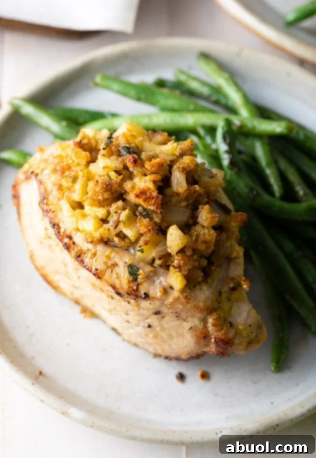 A vibrant side view of a plated apple stuffed pork chop with green beans, highlighting its appealing presentation.