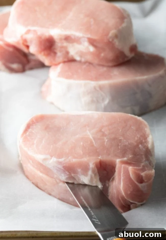 Close-up of prepared pork chops on a cutting board, showing the neatly cut pockets for stuffing.