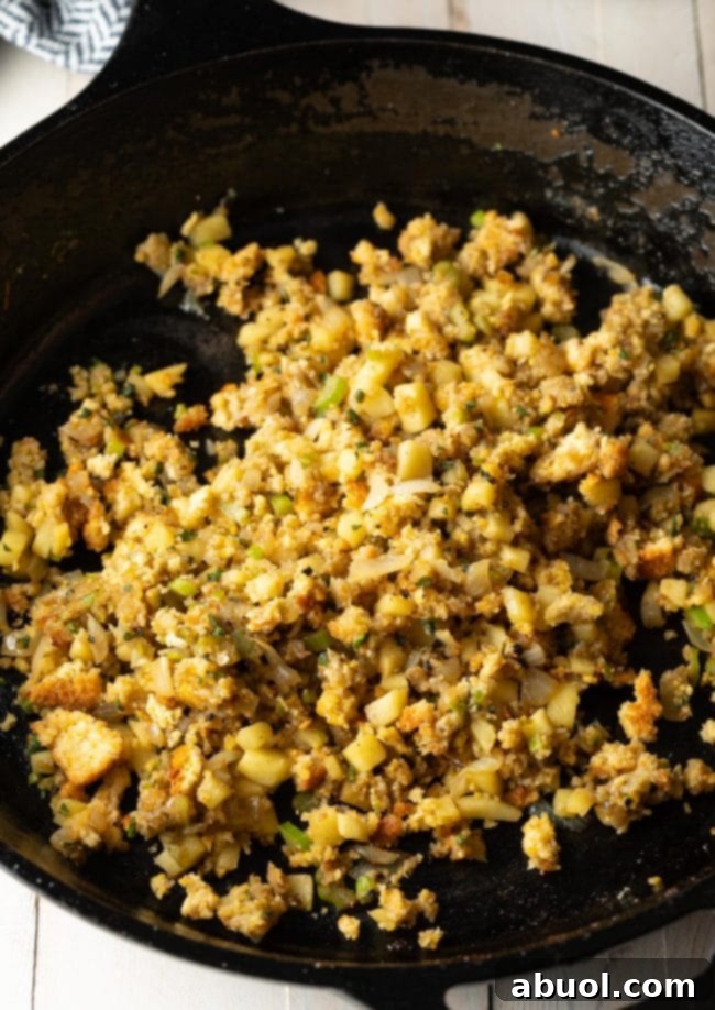 A close-up of a skillet filled with the savory apple and cornbread stuffing mixture, glistening and ready for the pork chops.