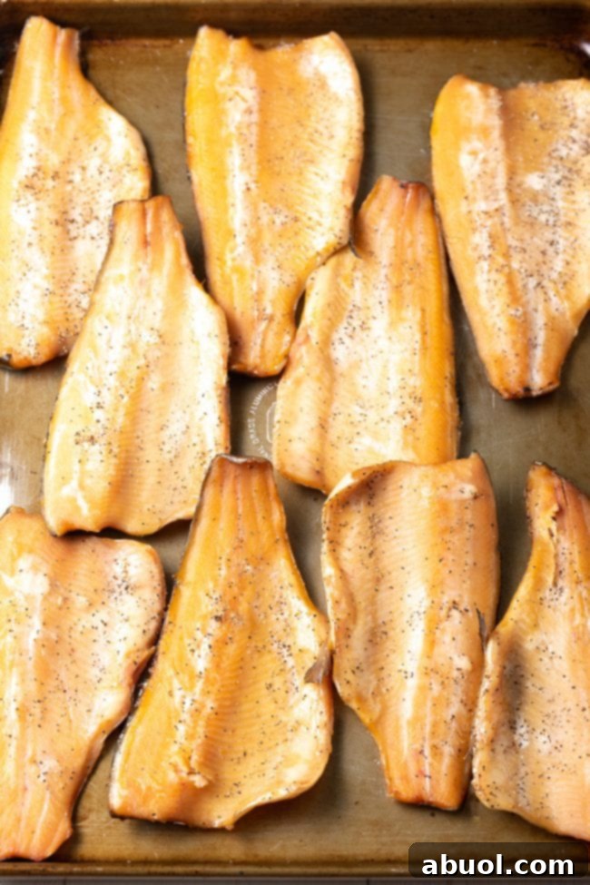 Smoked trout filets lined up on a baking sheet. 