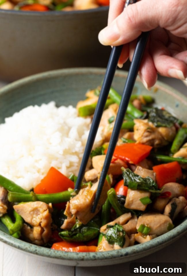 A bowl of freshly cooked Pad Krapow Gai with chopsticks, highlighting the vibrant colors and appealing texture of the dish.