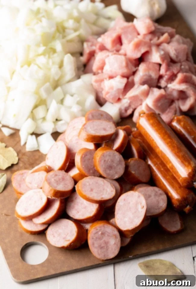 Freshly chopped onions, along with various cuts of ham and sausages, neatly arranged on a rustic wooden cutting board, ready for preparation.