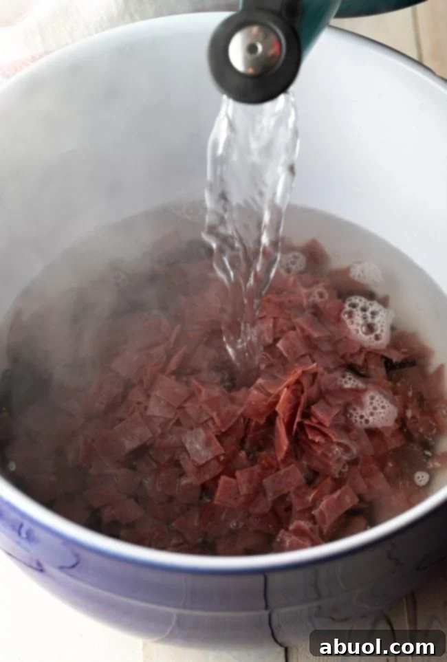 Dried beef and black beans are seen soaking in a large stew pot, with boiling water being poured over them, initiating the rehydration process for a rich stew.