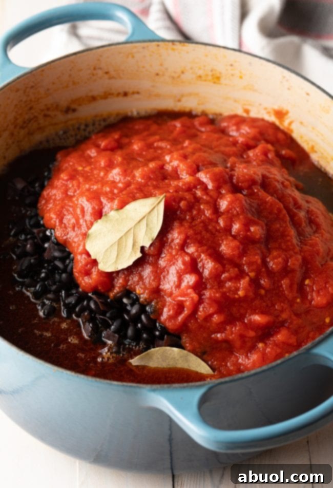 A large pot brimming with the rich, dark ingredients of Brazilian Feijoada, including various pork cuts, black beans, tomatoes, and spices, all simmering together.
