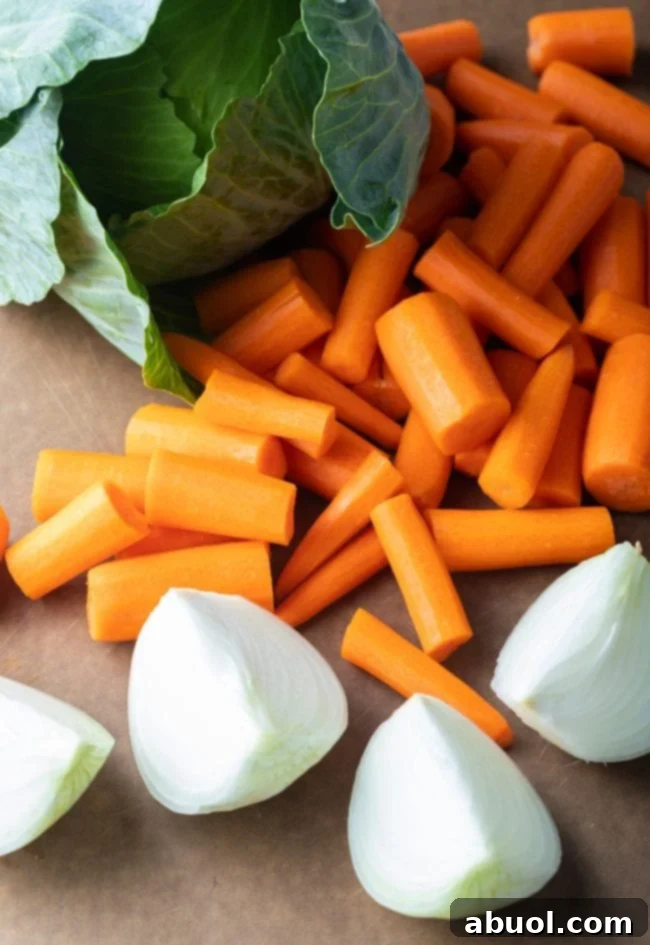 Fresh green cabbage, vibrant carrots, and a sweet onion on a cutting board, prepped for cooking.