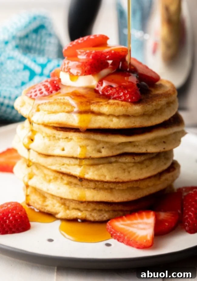 Stacked almond flour pancakes with fresh berries, maple syrup, and a pat of butter, illustrating a perfect gluten-free and dairy-free breakfast