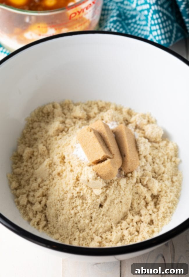 Dry ingredients for almond flour pancakes, including almond flour, brown sugar, baking powder, salt, and cinnamon, perfectly measured in a large mixing bowl