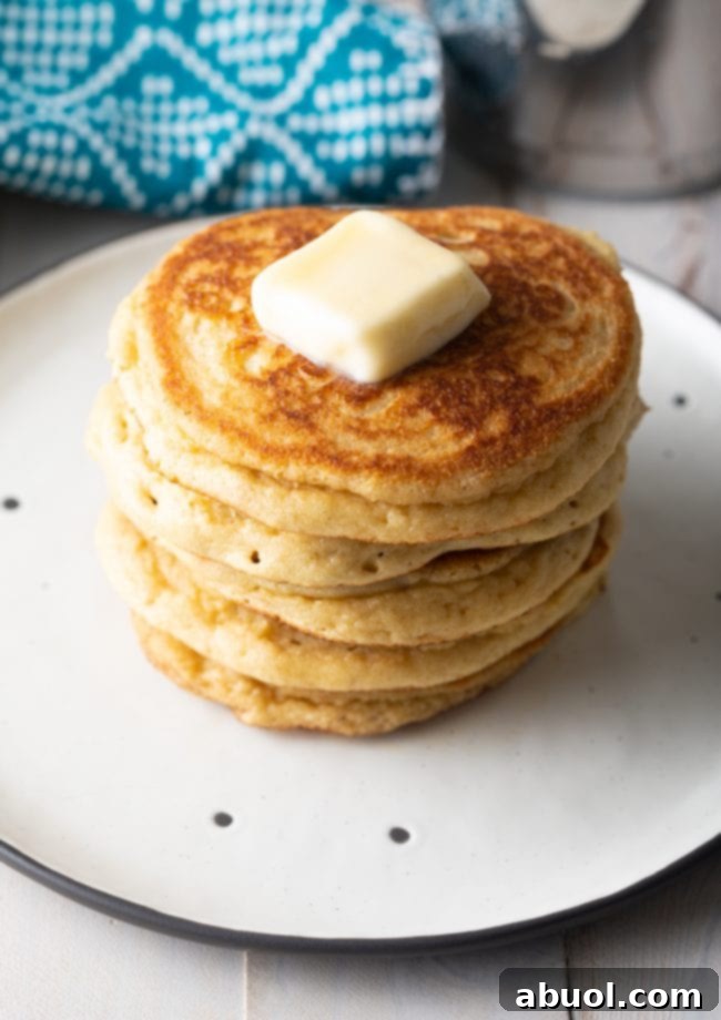 A beautiful stack of freshly cooked almond flour pancakes crowned with a melting pat of butter, inviting you to indulge in this delightful breakfast