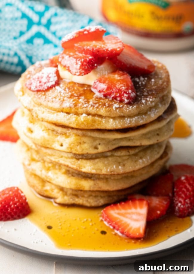 The ultimate almond flour pancake breakfast spread, featuring a stack of pancakes generously topped with fresh berries, a dollop of butter, maple syrup, and a light dusting of powdered sugar
