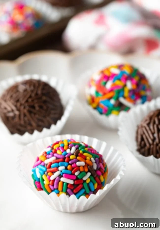 Close up of chocolate Brazilian truffles covered with chocolate and rainbow sprinkles on a plate. 