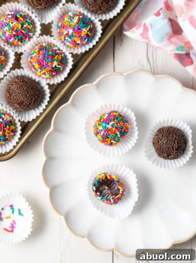Overhead shot of Brazilian truffles with sprinkles on a plate. One of the truffles is half eaten. 