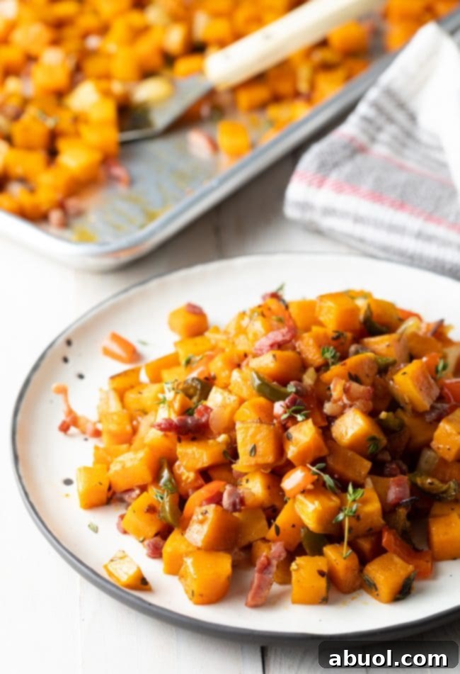 Sweet potato hash browns served on a white plate, with more hash browns visible on a baking sheet in the background.