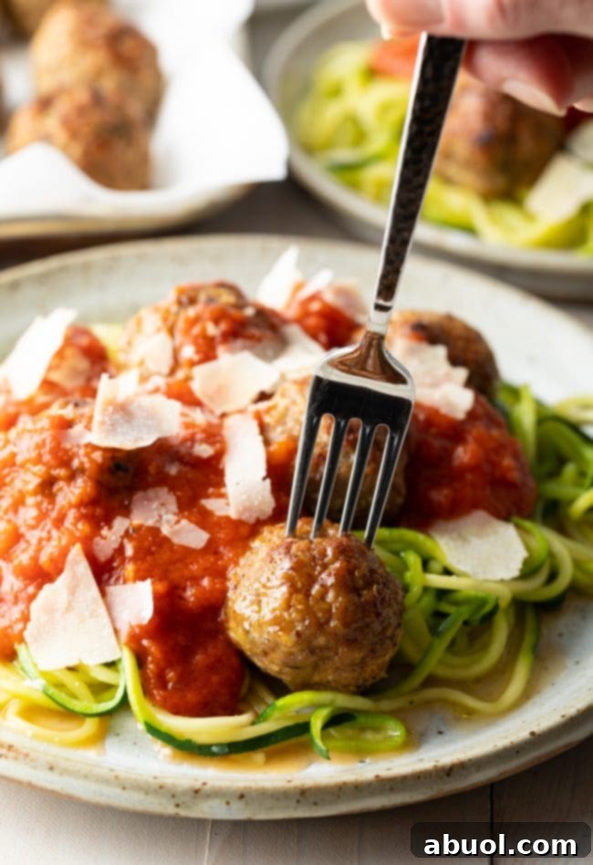Close-up shot of juicy ground turkey meatballs served with green zucchini noodles, highlighting a healthy meal option.