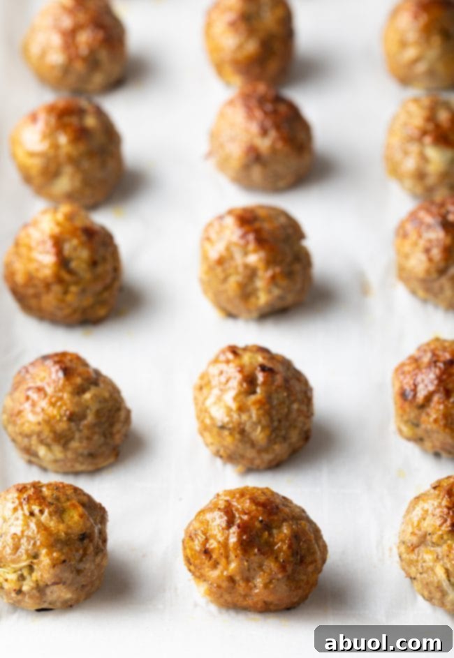 Close-up of perfectly baked low-carb turkey meatballs on a parchment-lined baking sheet, golden and firm.