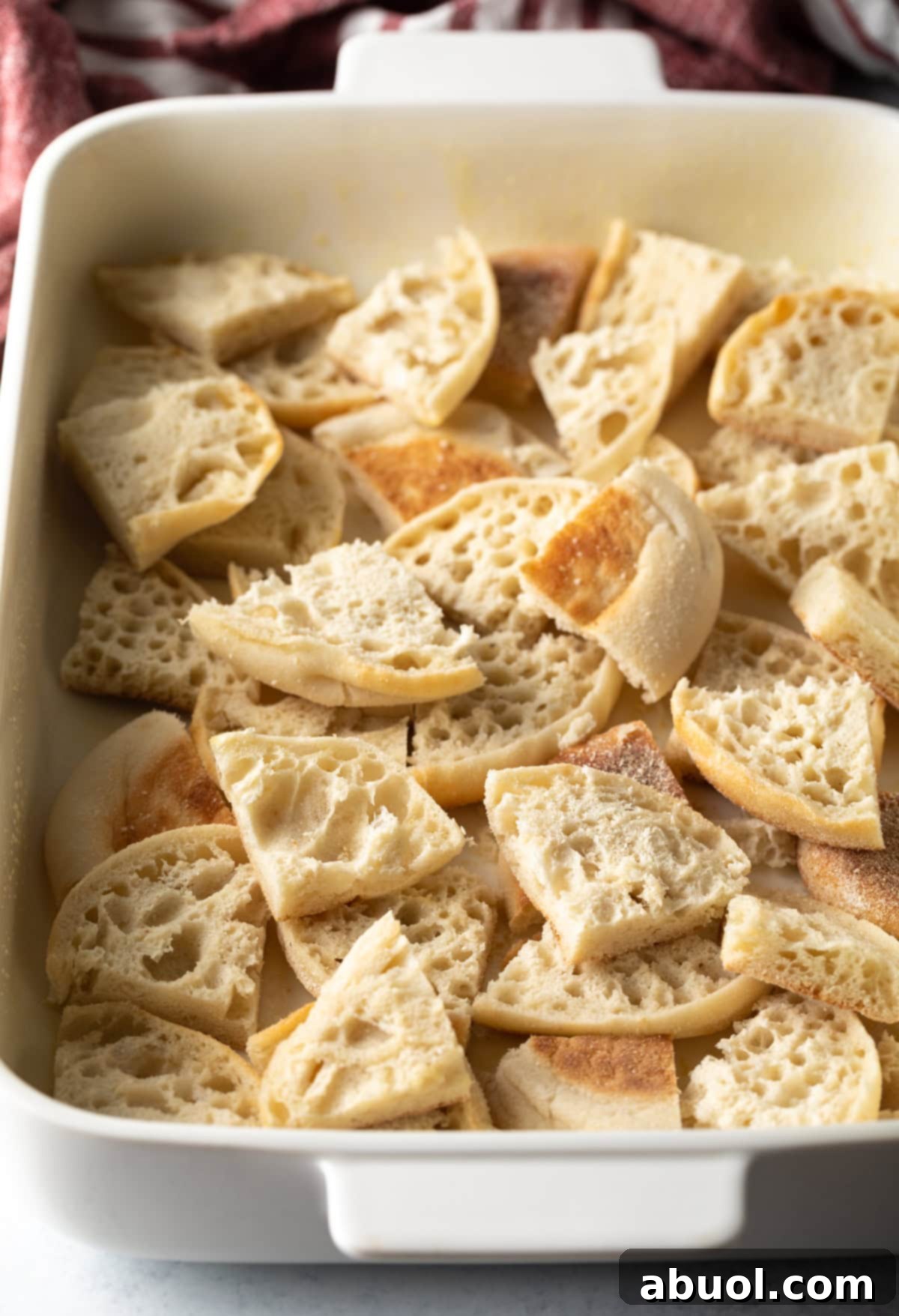 Quartered English muffins layered in a baking pan
